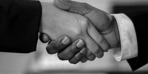 Grayscale Photo of Two People Shake Hands